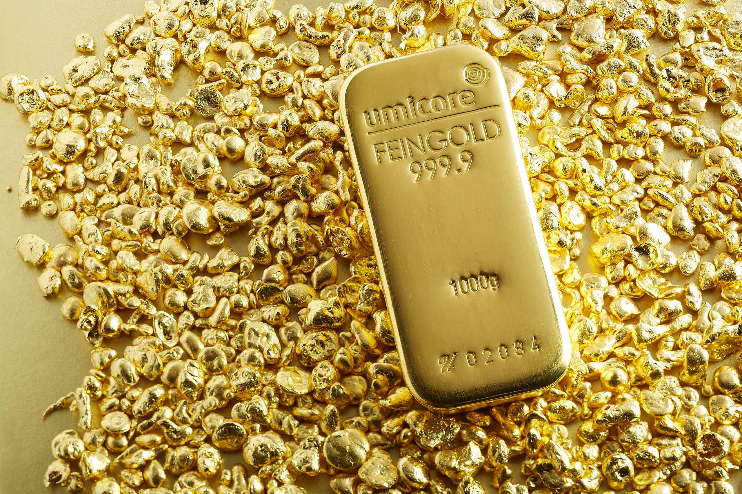 Fiscalidad metales preciosos — Un lingote de oro Umicore de 1kg, encima de una pequeña montaña de virutas de oro